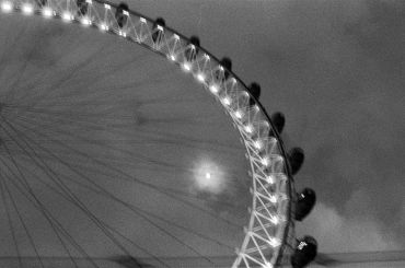 Black and white image of a Ferris wheel at night.