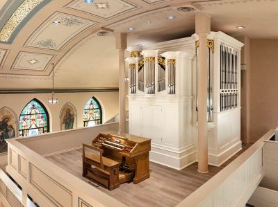 Church pipe organ and console with stained glass windows.