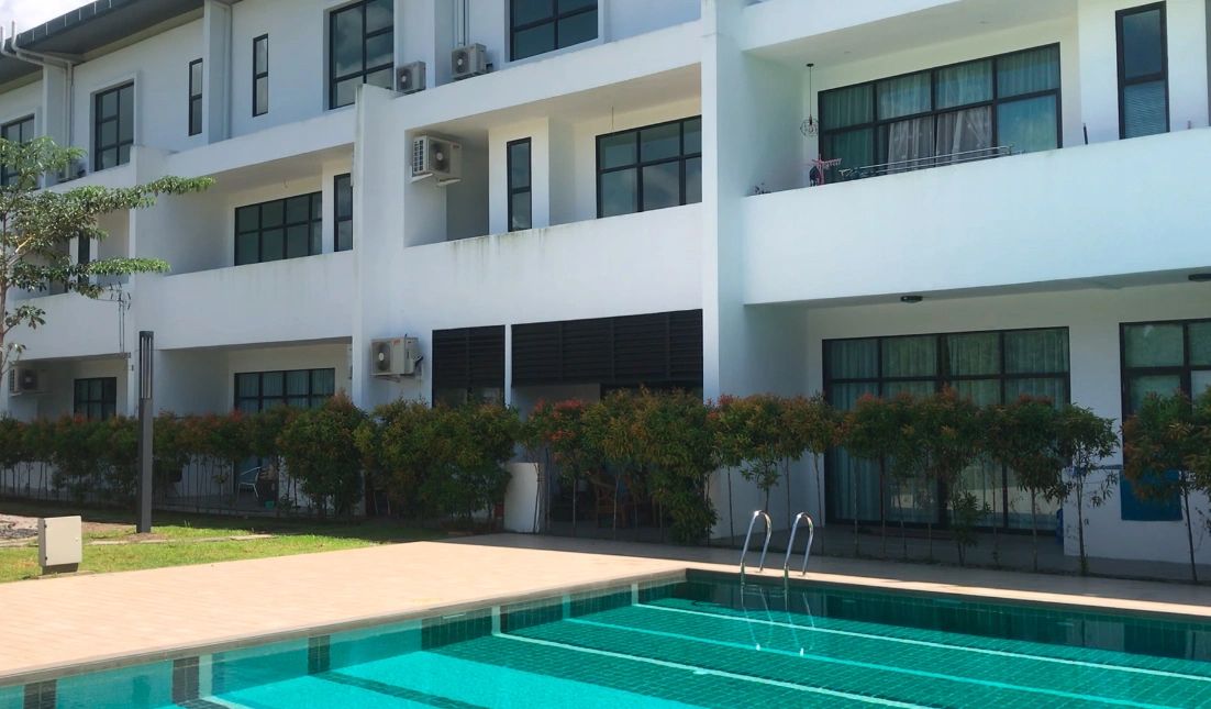 Modern white building with large windows and a clear swimming pool in front.