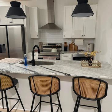 Modern kitchen with marble island and black pendant lights.