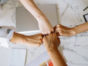 Four people bump fists over a table.
