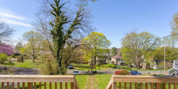 View from a wooden deck overlooking a green backyard and suburban houses under a clear blue sky.