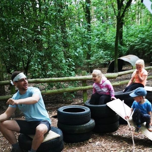  Children role playing in the woods. Sitting on a plane  made from tyres and planks of wood.