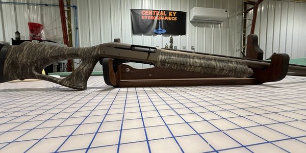 Camouflaged shotgun on display table.