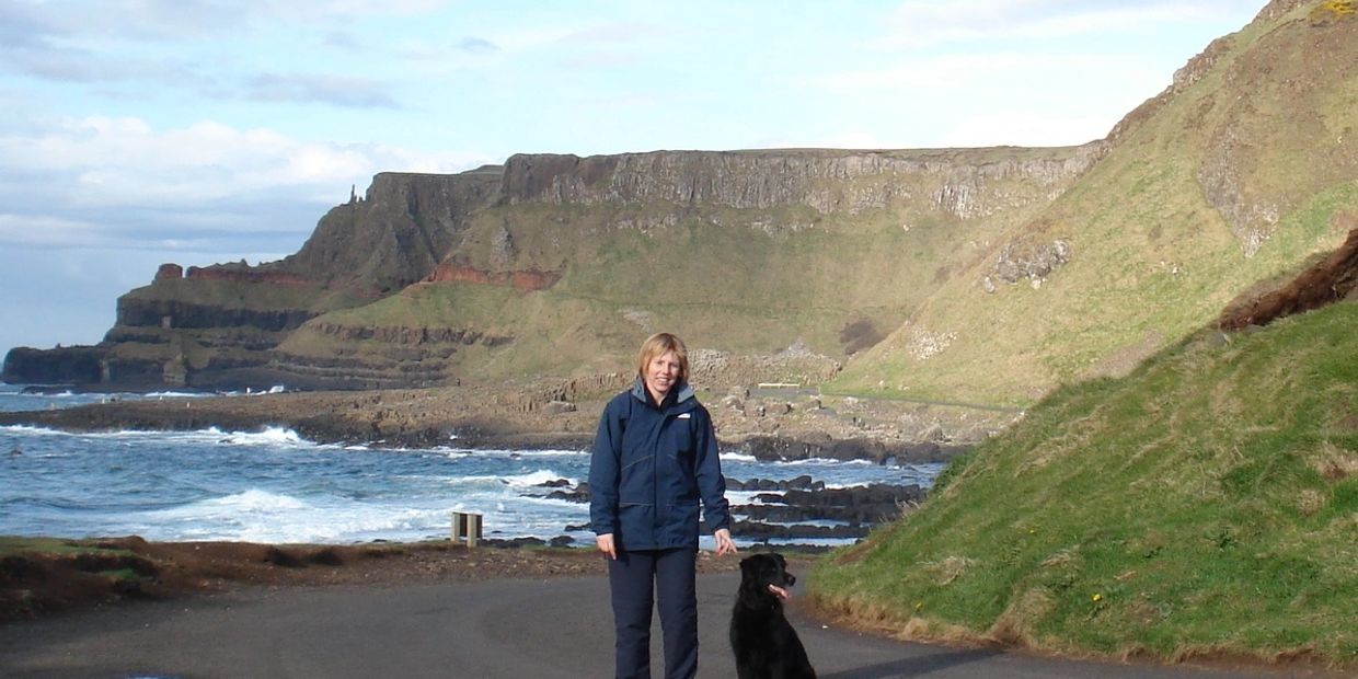 Dog Trainer with black dog sitting beside her at Giant's Causeway, Northern Ireland