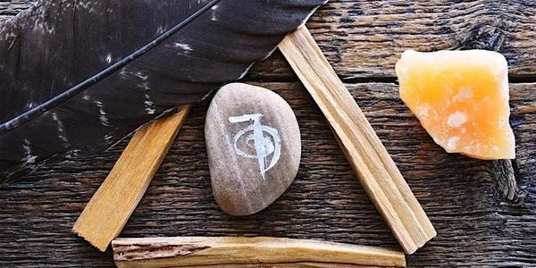 A stone with a symbol and natural elements arranged on wood.