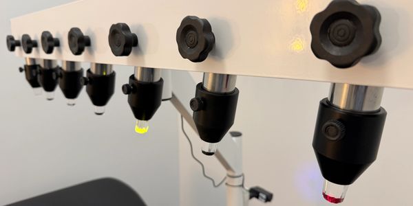 Close-up of multiple adjustable knobs with colored tips on a white panel.