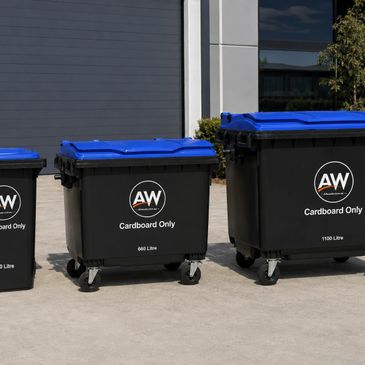 Three black cardboard recycling bins with blue lids outside a building.