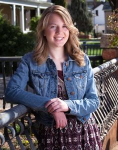 Portrait of Kassidy Price, a young, woman with blonde hair. She is wearing a denim jacket and dress.