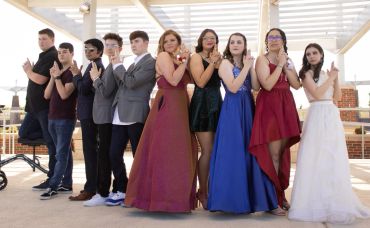 Group of young people posing with crossed arms in formal attire.