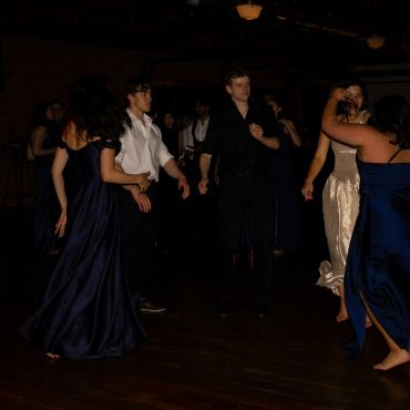 People dancing in a dimly lit room at a formal event.