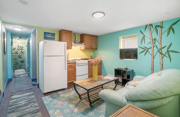 Cozy living space with kitchenette, teal walls, and bamboo mural.