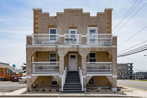 Symmetrical two-story beige building with white railings and central stairs.