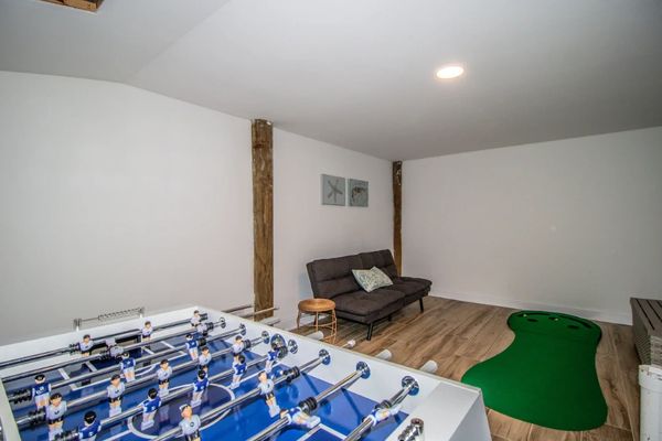 Basement game room with foosball table, sofa, and mini putting green.