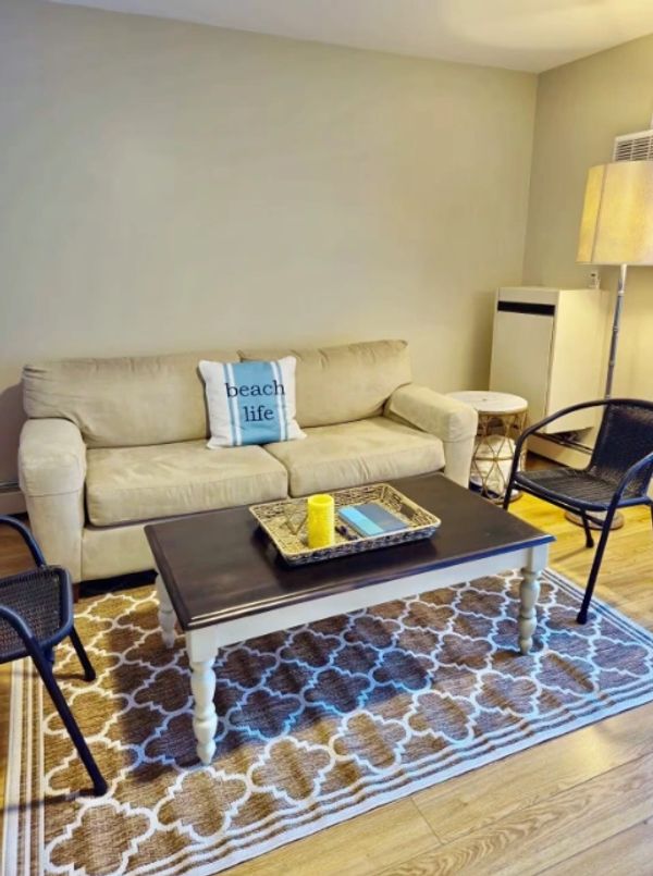 Cozy living room with beige sofa, patterned rug, and black chairs.