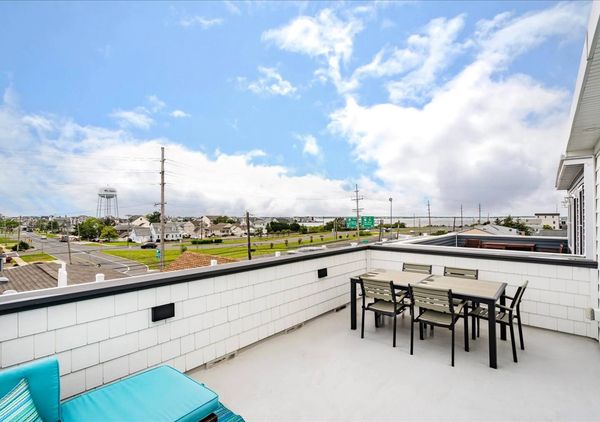 Spacious rooftop patio with outdoor dining and seating, overlooking a suburban neighborhood and water tower.
