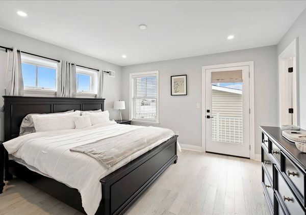 Bright bedroom with black furniture and white bedding.