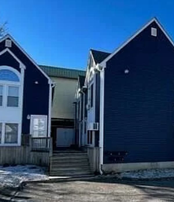 Two blue residential buildings connected by a small passage under a clear sky.