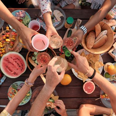 Group gathering around a table full of juices, fruits, cheese and meats.