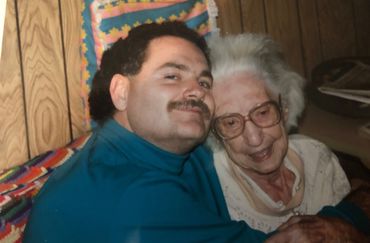 A man embraces an elderly woman with affection in a cozy room.