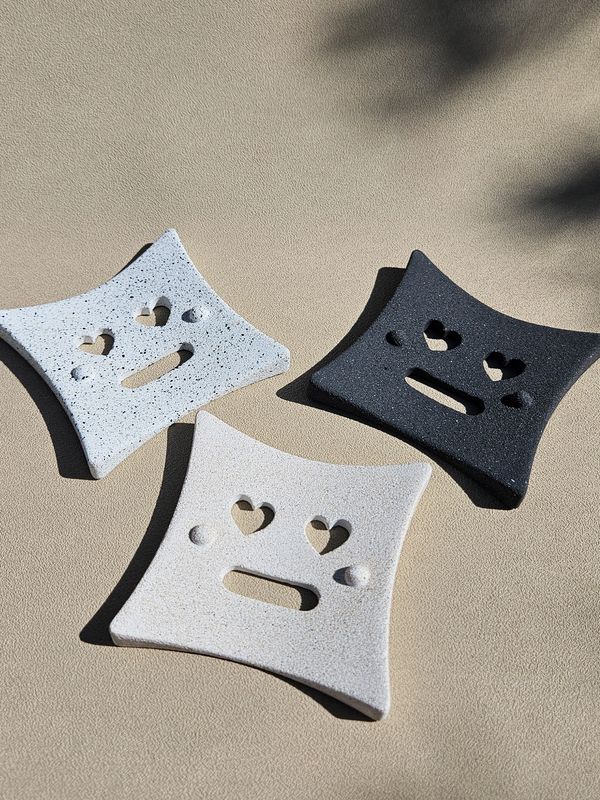 Three square ceramic dishes with heart-shaped eye cutouts and unique facial expressions.