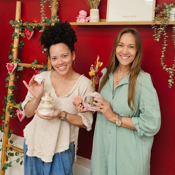 Two women smiling, holding handmade pottery and dried flower decorations.