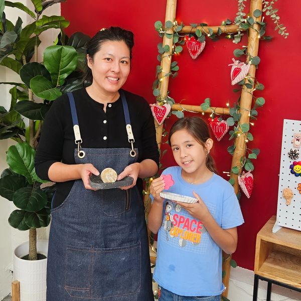 Woman and girl holding decorated cookies in a festive setting.