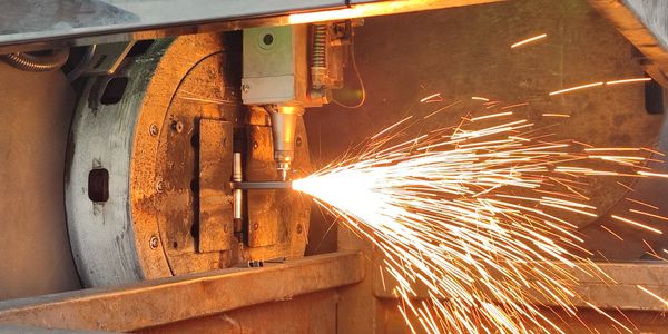Industrial machine cutting metal with sparks flying.