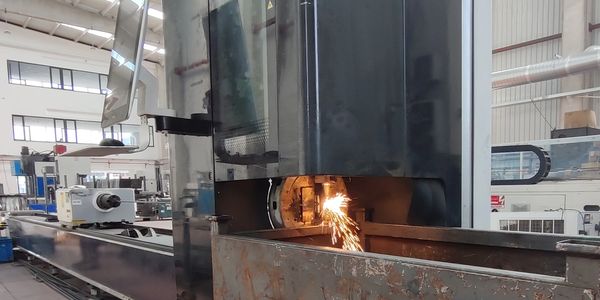 Industrial machine cutting metal with sparks flying inside a factory.