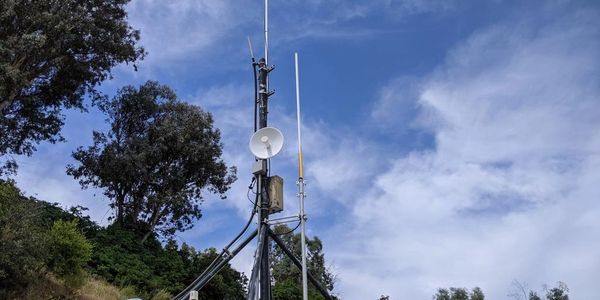 Communication antennas and equipment against a blue sky with clouds.