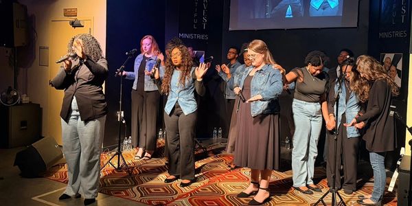 Group of women singing on stage with microphones.