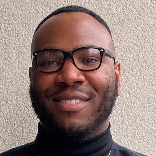 Man smiling with glasses and beard.