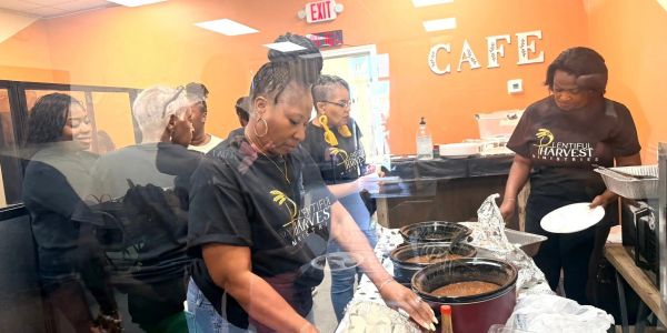 Volunteers serve food at a community cafe event.