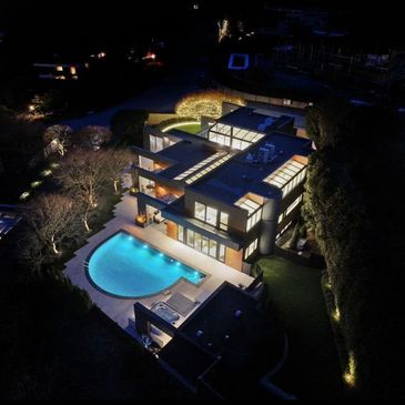 A modern house illuminated at night with a glowing pool.