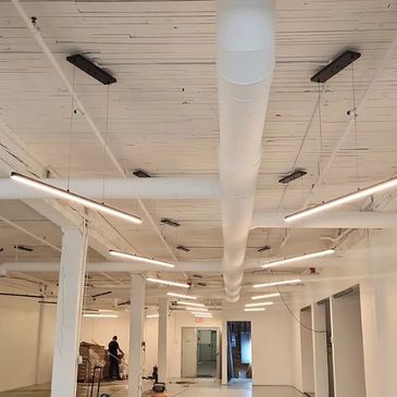 Modern industrial ceiling with white pipes and linear lights.