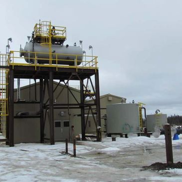 Industrial site with storage tanks and snowy ground.