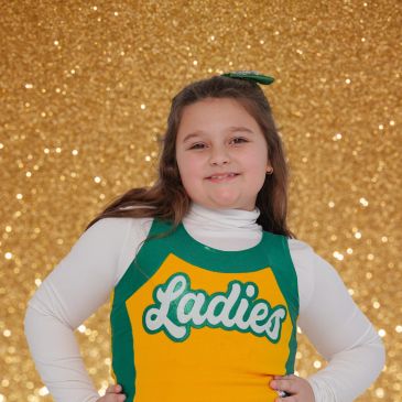 Young girl in cheerleading outfit smiling confidently.