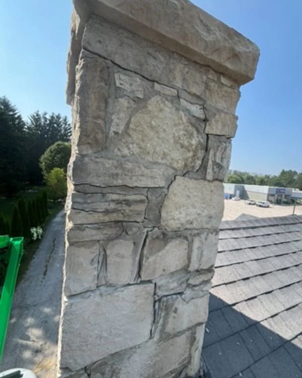 Stone chimney on a rooftop under a clear sky.