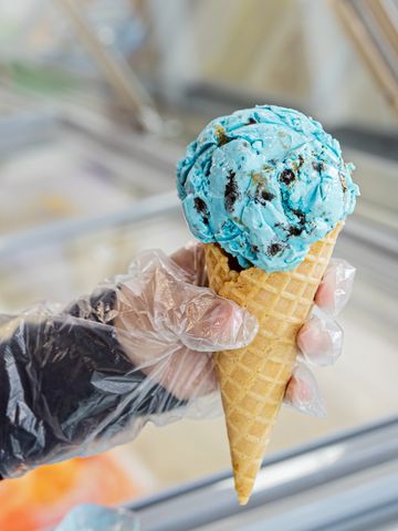 Hand holding a blue ice cream cone with chocolate chips.