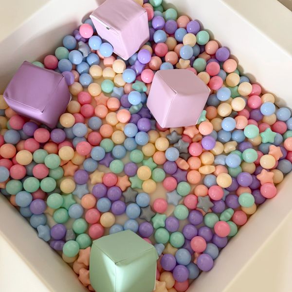 Colorful pastel balls and soft cubes in a playpen.