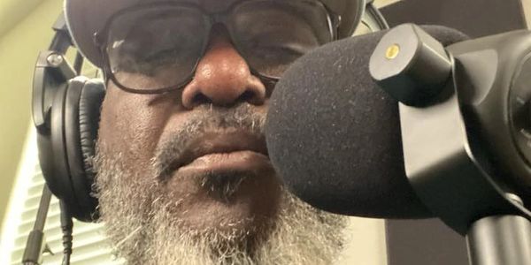 Man with headphones speaking into a microphone.