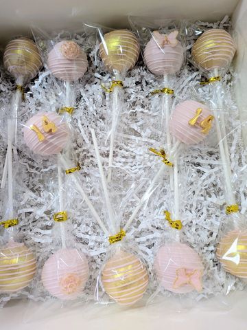 Elegant cake pops decorated with pink and gold accents in a gift box.