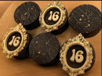 Elegant black and gold chocolates with the number 16 for a special celebration.