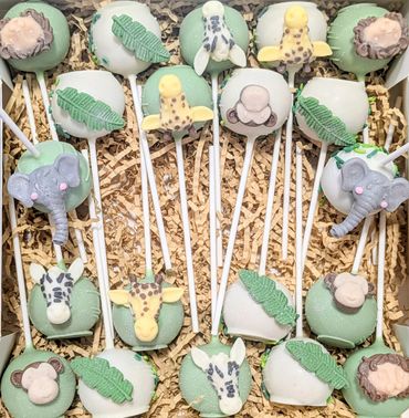 Animal-themed cake pops with leaves in a decorative box.