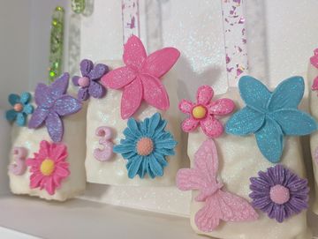 Decorative glittery flowers and butterflies on a white surface.