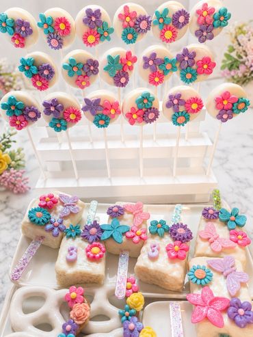 Colorful floral cake pops and decorated treats on sticks.