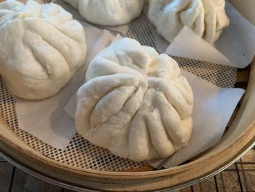 Steamed white buns in a bamboo basket.