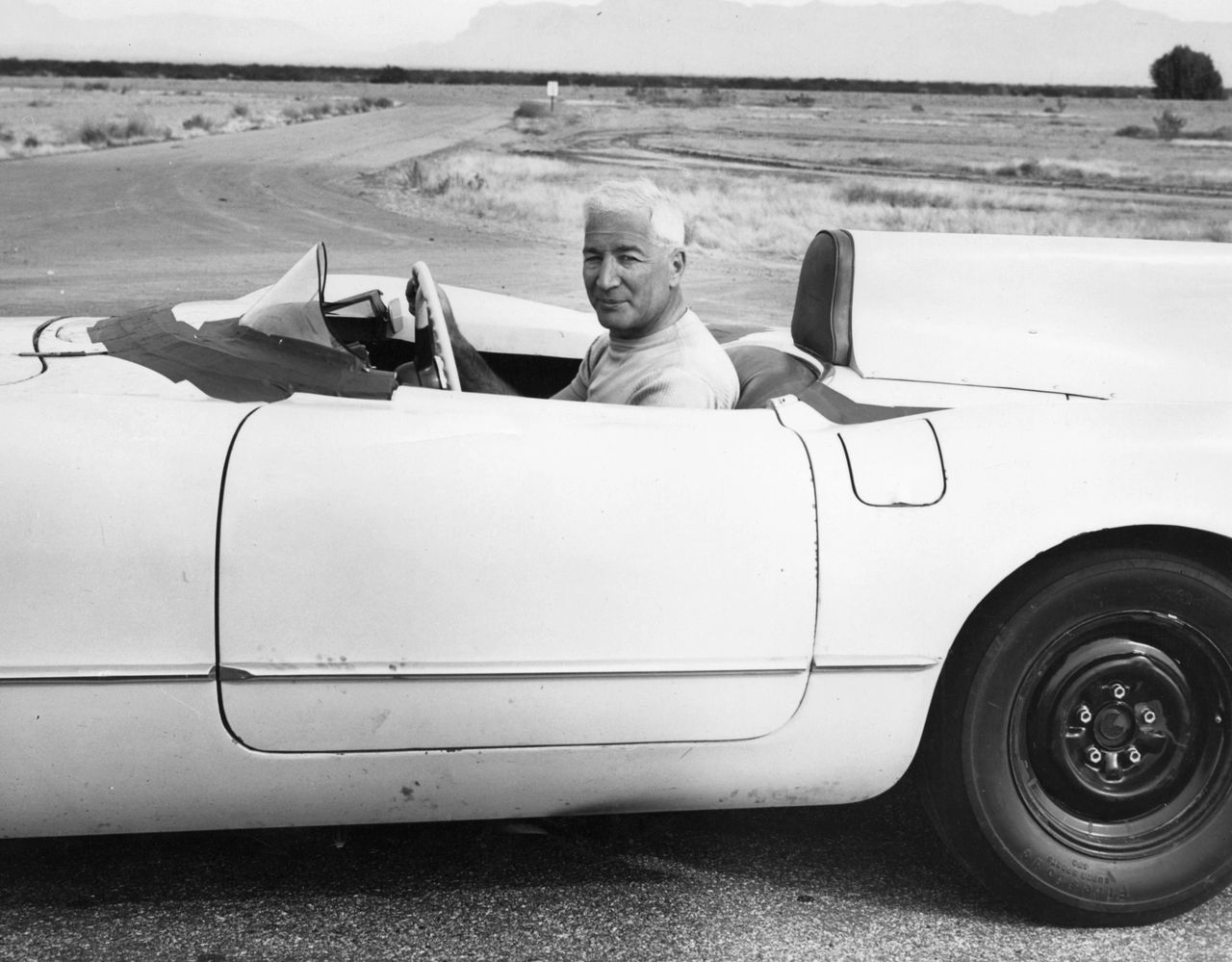 Photographed at the General Motors Arizona Proving Grounds in Mesa, this image captures Zora Arkus-Duntov during the decisive EX-87 high-speed sessions of December 1955—most notably the December 12, 1955 run that produced a two-way average of 156.16 mph, surpassing his 150-mph objective. The program didn’t stop there: after Duntov installed his hotter high-lift camshaft (paired with the rest of the engine’s evolved high-output configuration), the EX-87 returned with the breathing and rpm it needed to go further. In that later configuration, the car achieved a recorded top speed of 163 mph—turning a development exercise into a hard-number performance statement Chevrolet couldn’t ignore. (Image courtesy of GM Media LLC)