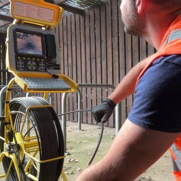 Worker operating a pipe inspection camera system.