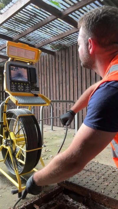 Man operating inspection camera device in an outdoor setting.